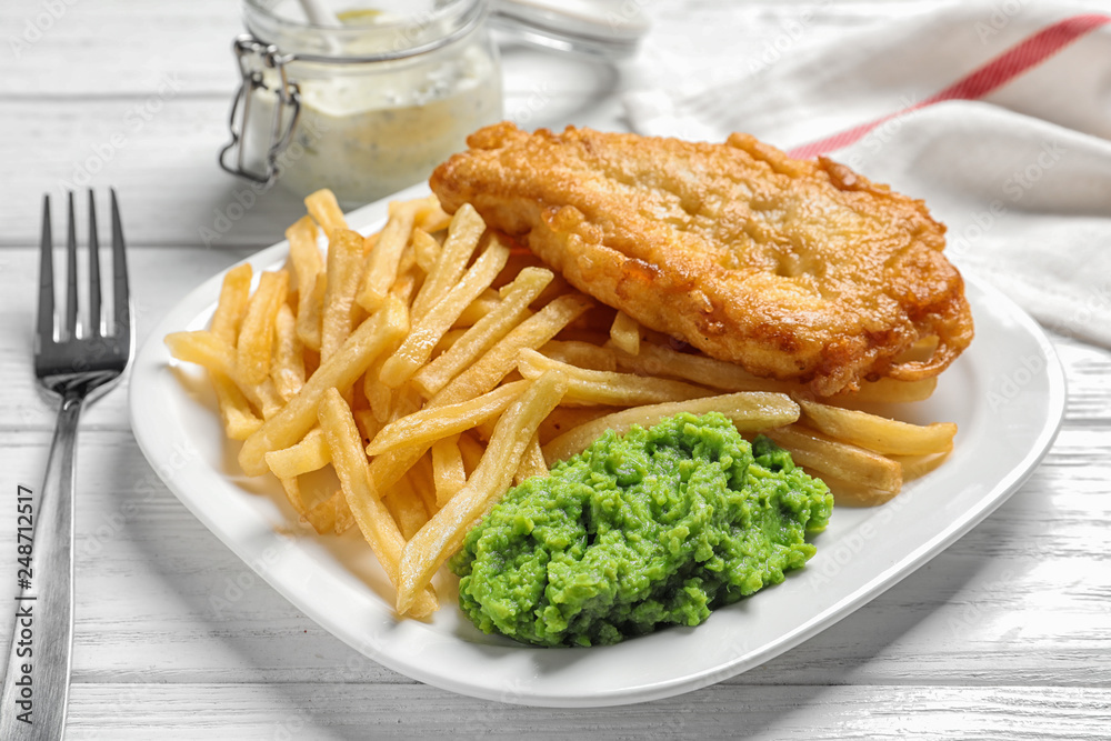 Plate with British traditional fish and potato chips on wooden background Plate with British traditional fish and potato chips on wooden background