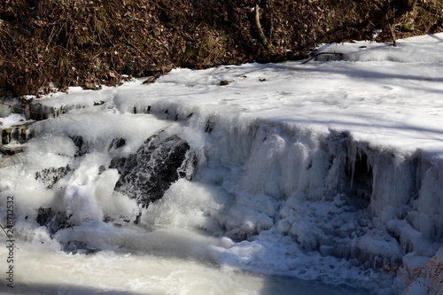 The frozen waterfall in the stream on a sunny cold day.