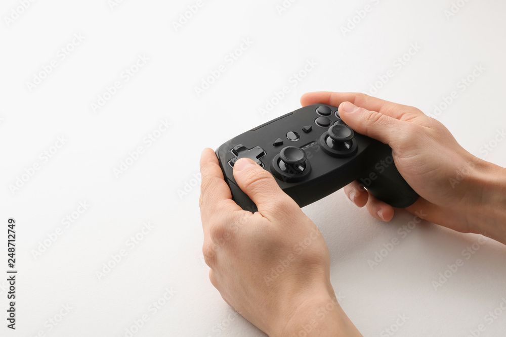 Young man holding video game controller on white background, closeup Young man holding video game controller on white background, closeup