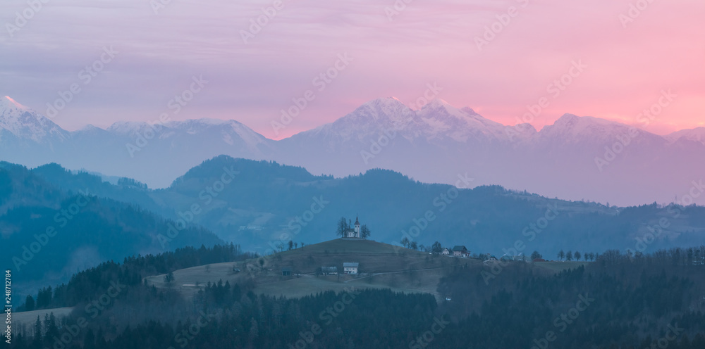 View of the alps in the morning with the st. Tomaz church on the top of the hill, Slovenia