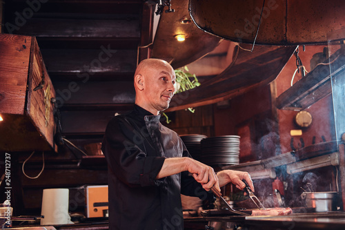 Master chef cooking delicious beef steak on a kitchen in a restaurant.