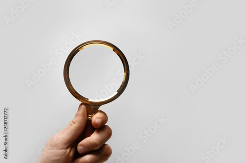 Woman holding magnifying glass on white background, closeup. Space for text