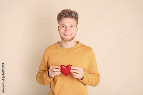 Portrait of young man with decorative heart on color background