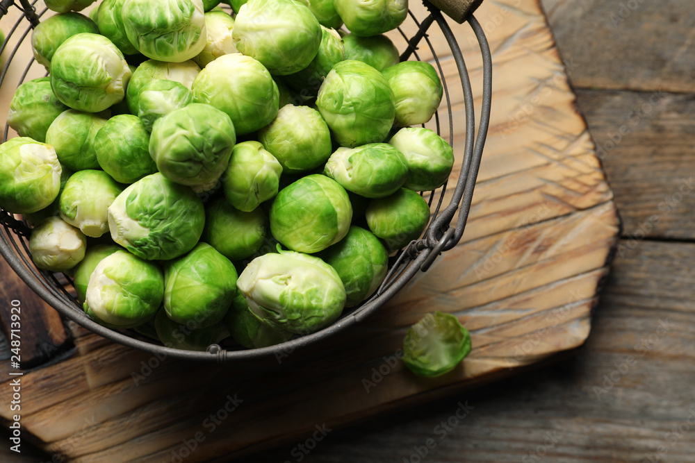 Metal basket with fresh Brussels sprouts on wooden background, top view Metal basket with fresh Brussels sprouts on wooden background, top view