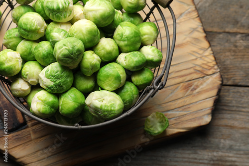 Metal basket with fresh Brussels sprouts on wooden background, top view