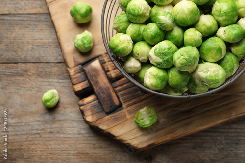 Metal basket with fresh Brussels sprouts on wooden background, top view. Space for text