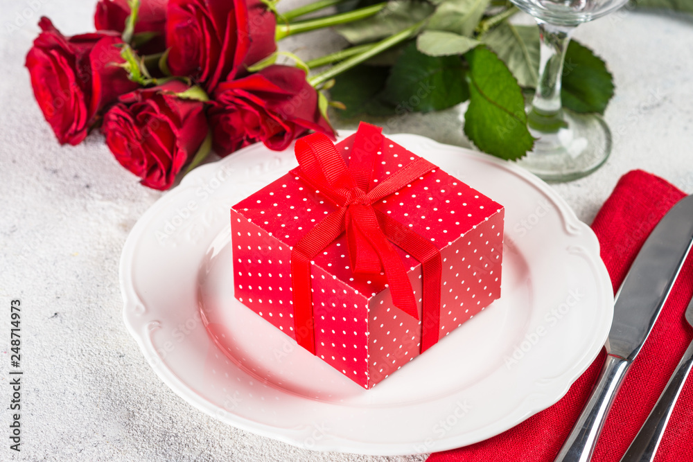 Holiday table setting with plate, roses and present. Holiday table setting with plate, roses and present.
