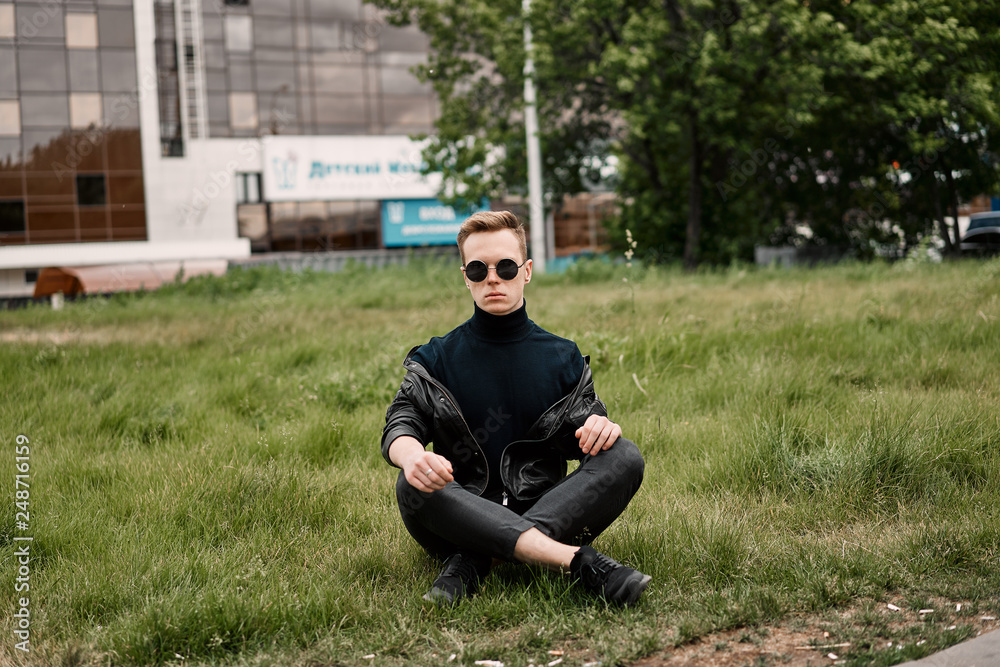 man in the hat wears sunglasses sitting on the grass man in the hat wears sunglasses sitting on the grass