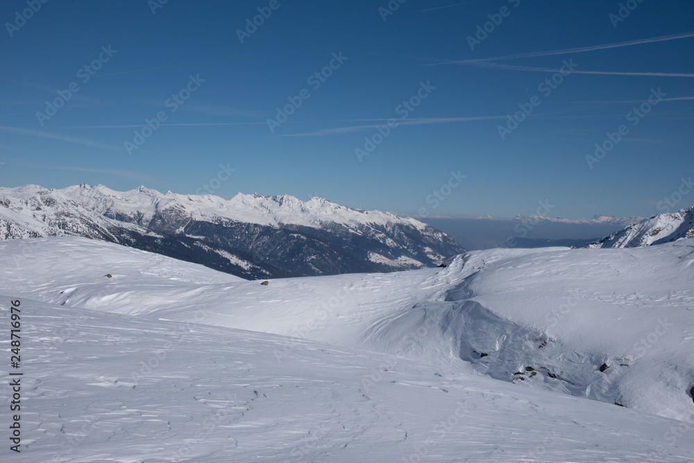 View of the mountains around the Tonale Pass from the Paradiso lodge during a winter sunny day. Tonale is a mountain pass between Lombardy and Trentino, near the Presena glacier