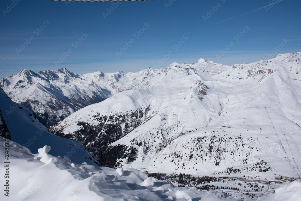 Obraz premium View of the mountains around the Tonale Pass from the Paradiso lodge during a winter sunny day. Tonale is a mountain pass between Lombardy and Trentino, near the Presena glacier