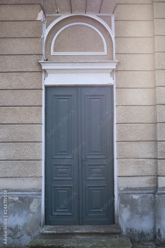 Drzwi drewniane szare do beżowego budynku - obrazy, fototapety, plakaty 