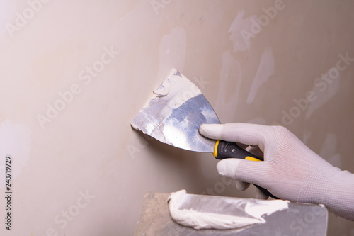 Hand with putty knife repair wall, Hand with a spatula, spatula with spackle paste structure, process of applying layer of putty trowel, working with spackling paste. photo