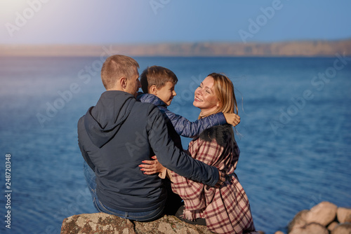 European family is spending their weekend near the beautiful lake, they are happy together, smiling and enjoying the serenity around.