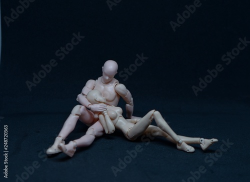 Two mannequin art models representing a romantic embrace on black background. concept of feelings