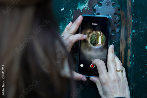 Rome, February 07, 2018: A tourist takes a pictures of St. Peter's dome through the keyhole on the gate to the headquarters of the Knights of Malta on Rome's Aventine Hill. Peek through this keyhole o photo