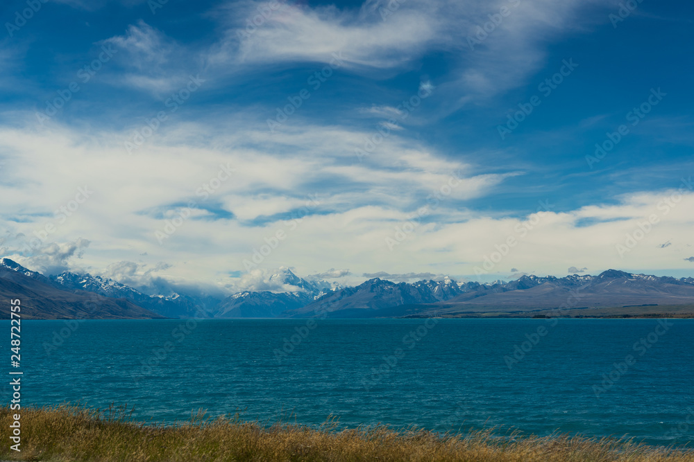 Lake Pukaki view from Glentanner Park Centre near Mount Cook, on a background of blue sky with clouds, snowy Southern Alps