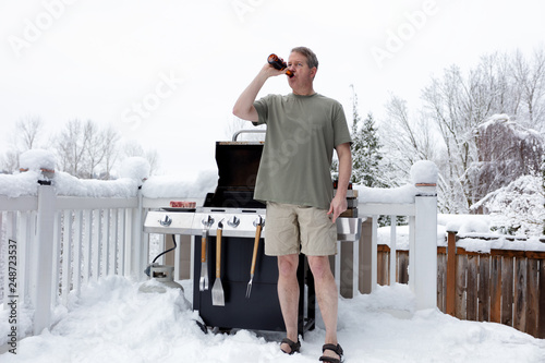 Photography Mature man getting ready to grill while drinking beer during winter season