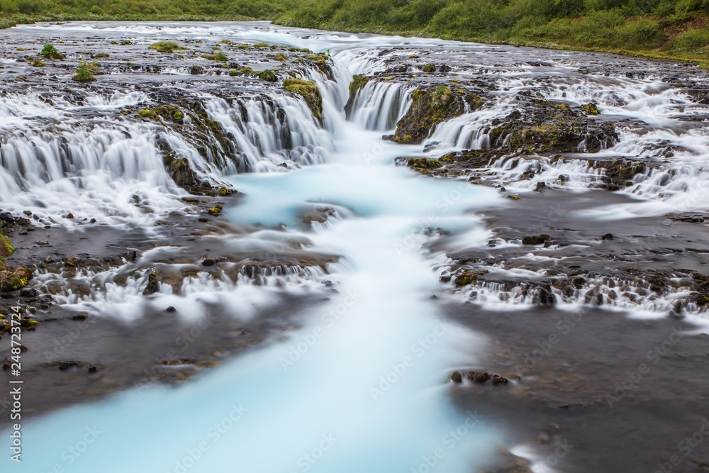 Detail of bright powerful Bruarfoss waterfall in Iceland with cyan water blurred by long exposure. Popular tourist attraction. Unusual and picturesque scene. Location place South Iceland, Europe Detail of bright powerful Bruarfoss waterfall in Iceland with cyan water blurred by long exposure. Popular tourist attraction. Unusual and picturesque scene. Location place South Iceland, Europe