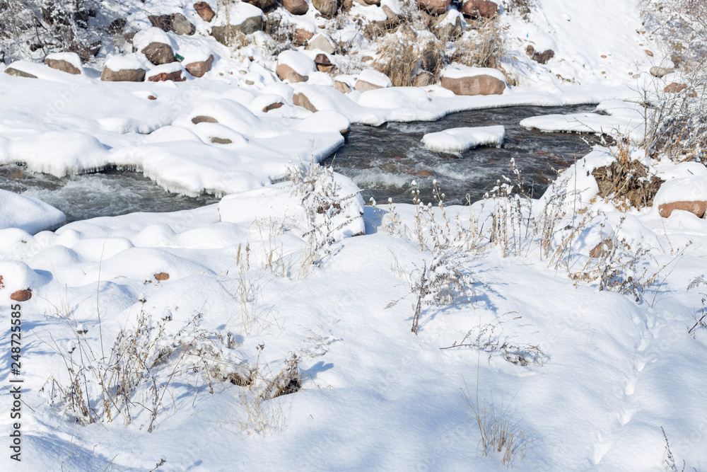 smooth movement of wild water in a river in winter with snow and ice on rocks and stones in beautiful nature smooth movement of wild water in a river in winter with snow and ice on rocks and stones in beautiful nature