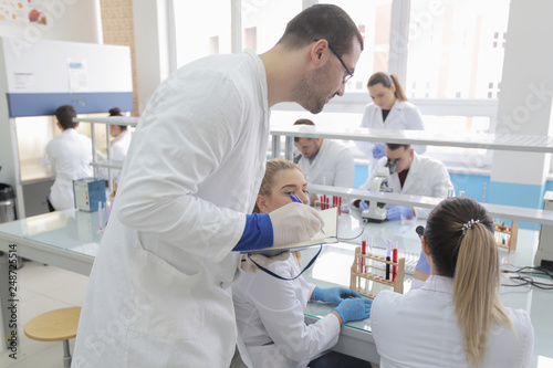 Fototapeta Naklejka Na Ścianę i Meble -  Group of young Laboratory scientists working at lab with test tubes and microscope, test or research in clinical laboratory.Science, chemistry, biology, medicine and people concept.