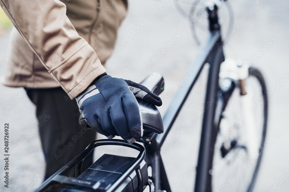 Obraz premium A midsection of a cyclist with electrobike standing outdoors in town.