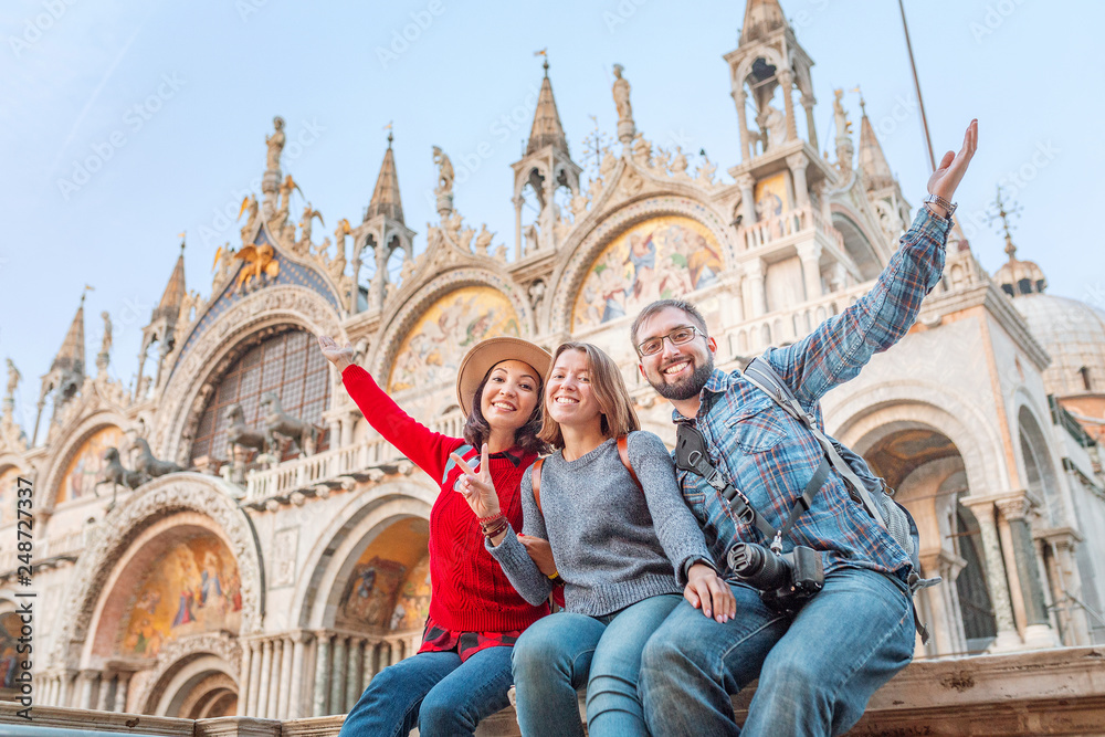 Group of happy friends travelers having fun on San Marco Square in Venice. Vacation and holidays in Italy and Europe concept