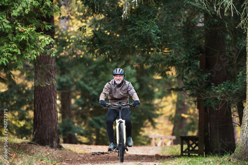 A senior man with electrobike cycling outdoors on a road in park in autumn. © Halfpoint