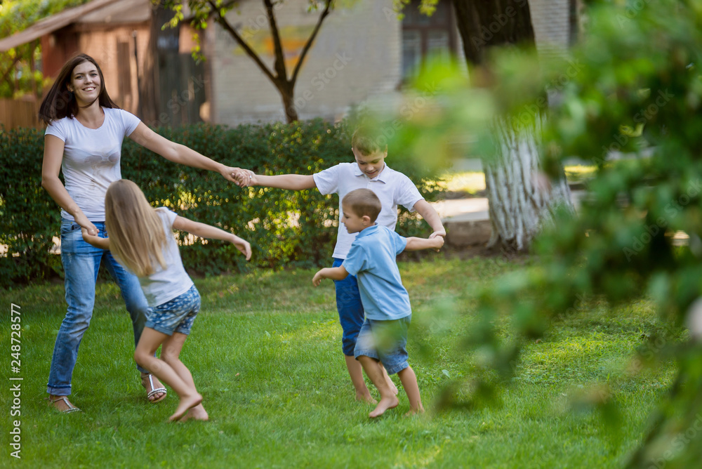 Mother and children dance on the lawn in the park