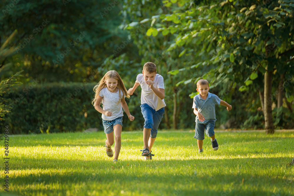 Boys and girl play and run a race on the lawn outdoor