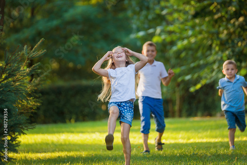 Boys and girl play and run a race on the lawn outdoor