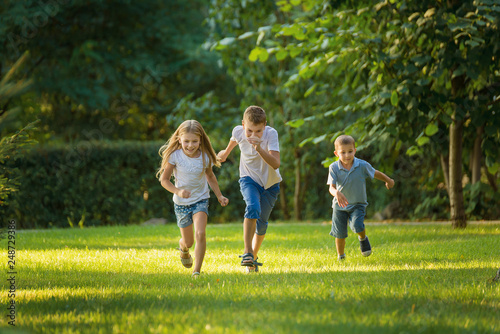 Boys and girl play and run a race on the lawn outdoor