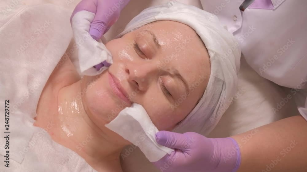 The rejuvenating effect of the skin on the face of a woman. Close-up. Cosmetic procedure on the female face in the beauty salon. A beautician cleans a woman's face with wet wipes. The rejuvenating effect of the skin on the face of a woman. Close-up. Cosmetic procedure on the female face in the beauty salon. A beautician cleans a woman's face with wet wipes.