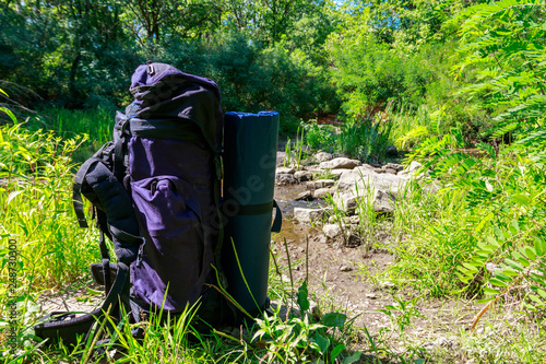 Tourist backpack near a river at summer. Hike concept