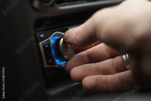 Close-up of man hand adjusts the volume control of car audio system 