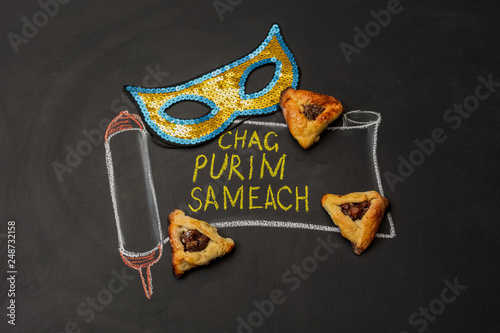 Obraz na płótnie Painted scroll with an inscription Happy Purim on a chalk board next to the carnival mask and Hamantaschen cookies w salonie