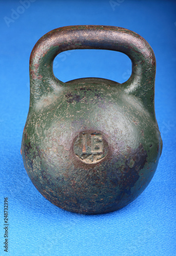 Old rusty weight for sports on a blue rug