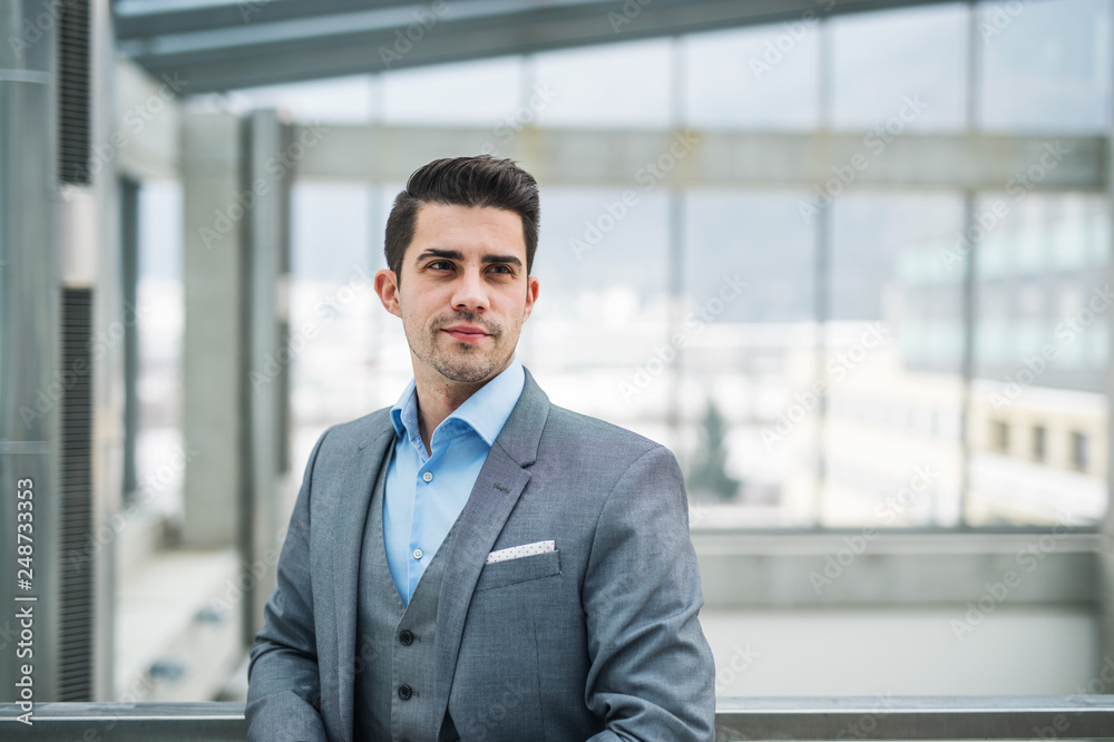 A portrait of young businessman standing in corridor outside office. Copy space. A portrait of young businessman standing in corridor outside office. Copy space.