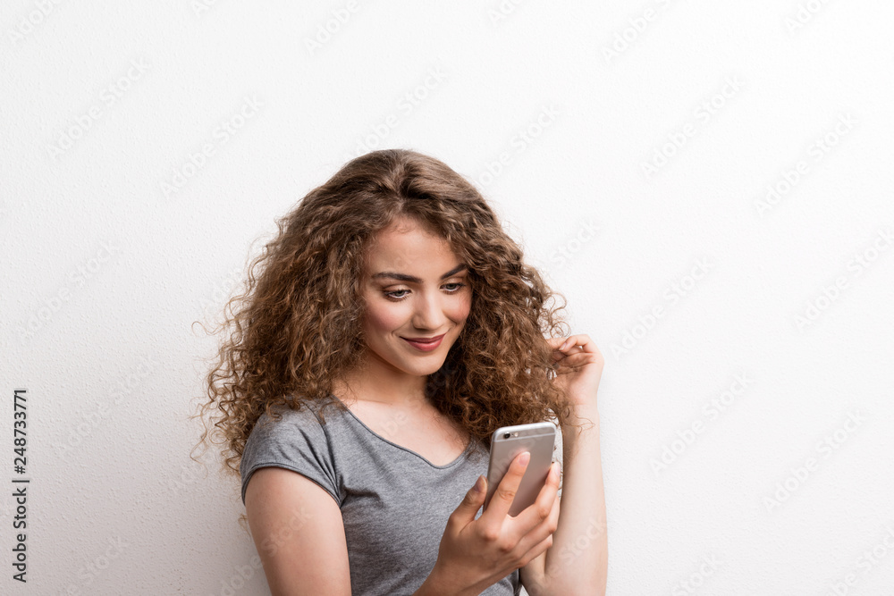Young beautiful happy woman in studio, using smartphone. Young beautiful happy woman in studio, using smartphone.
