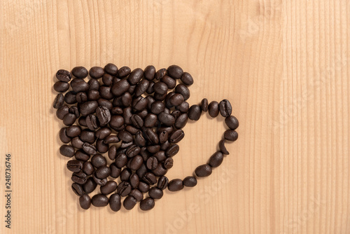 Coffee cup made from beans on wooden floor.