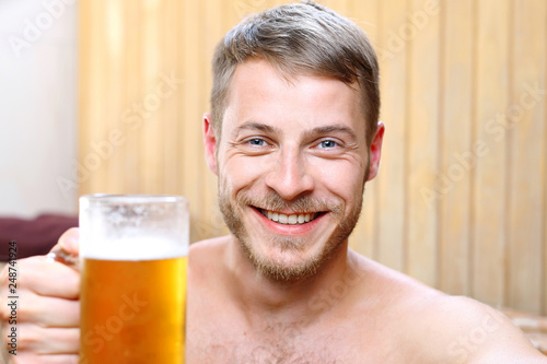 Kąpiel spa. Przystojny mężczyzna zażywa kąpieli w bali z woda termalną pijąc piwo kuflowe.