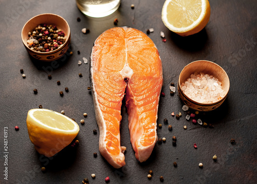 salmon steak with ingredients on dark stone background