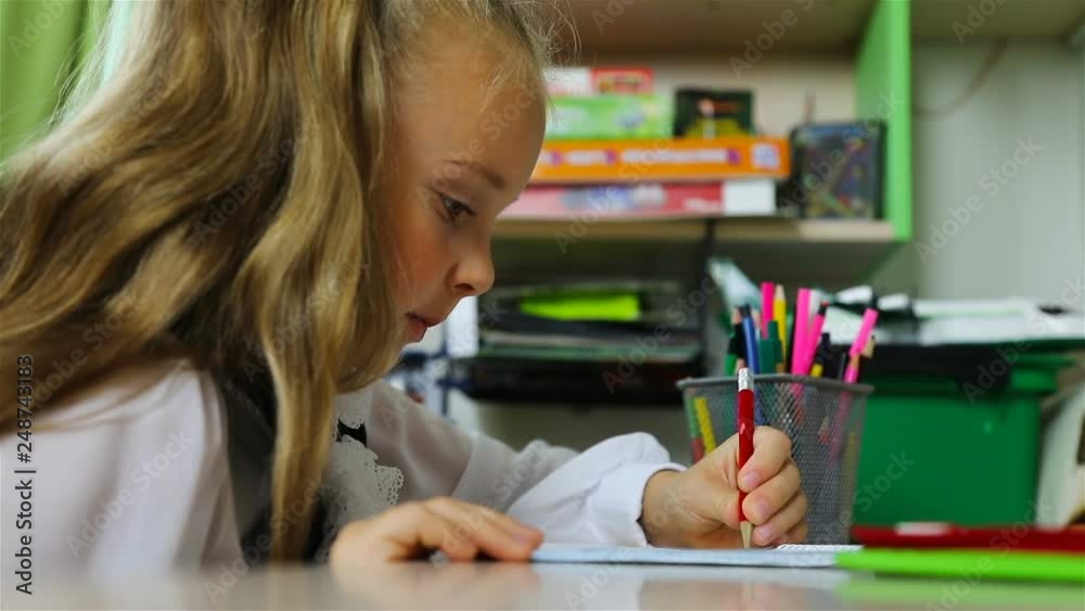 a schoolgirl draws in pencil and laughs. a schoolgirl draws in pencil and laughs.