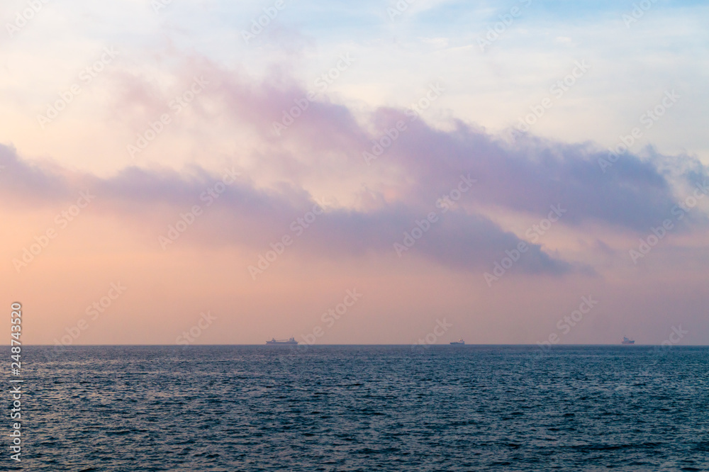 朝の海。染まる雲と船の影