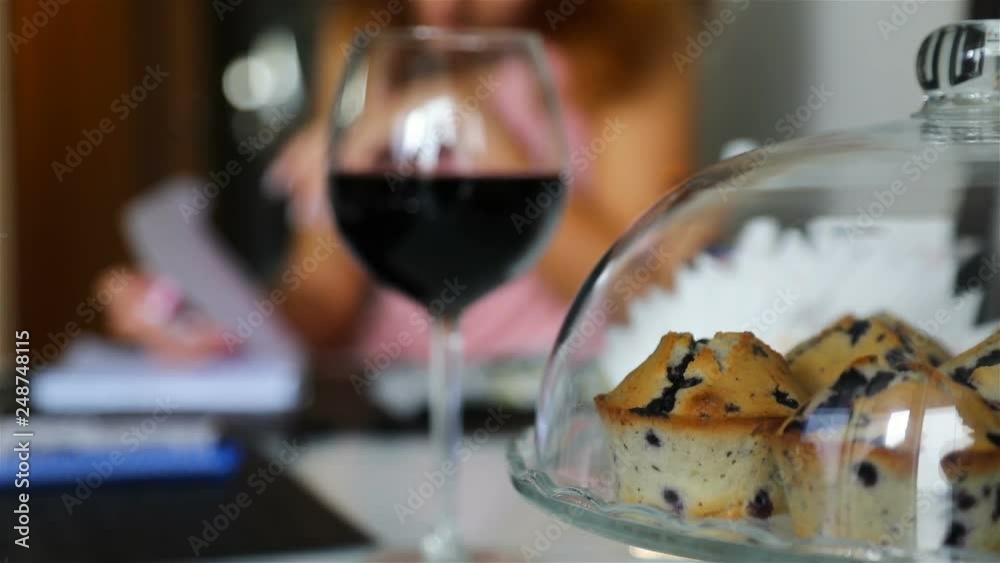 a girl with a glass of red wine and a tray of cupcakes. Blurred Background. a girl with a glass of red wine and a tray of cupcakes. Blurred Background.