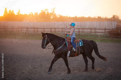 Fotografi girl riding black horse roping calves