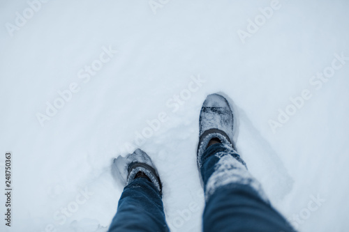 Top view of male legs walking on snow.