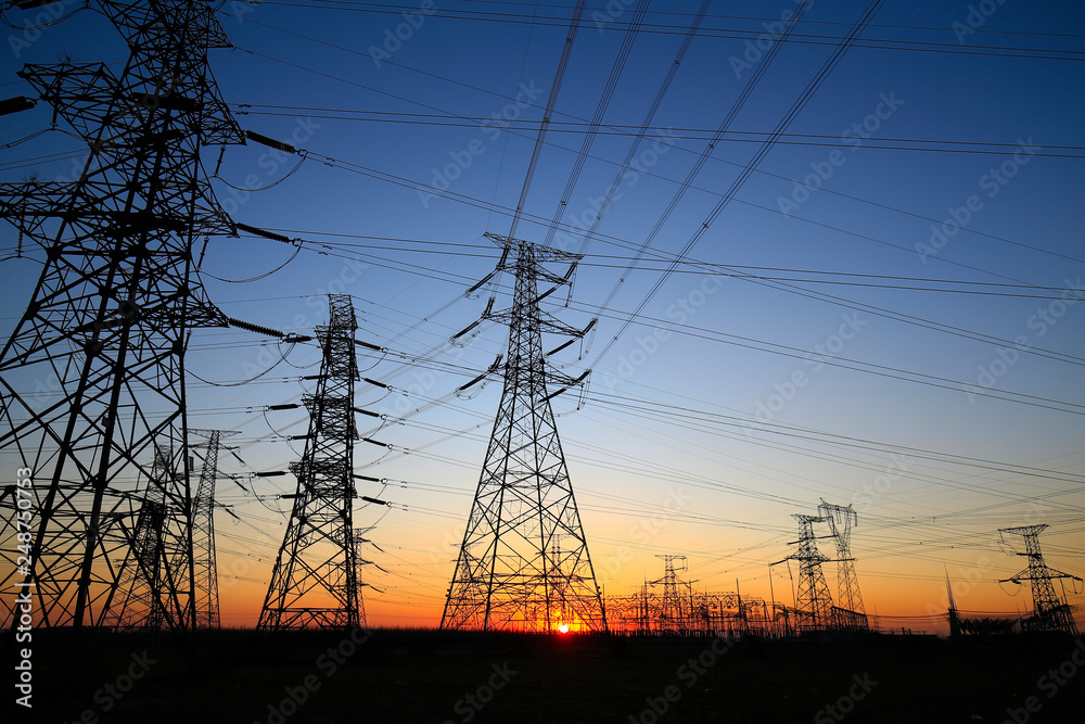 A high-voltage tower in the setting sun against the sky