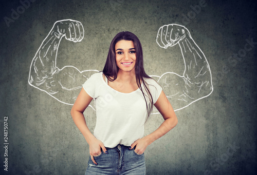 Strong happy young woman flexing her muscles photo