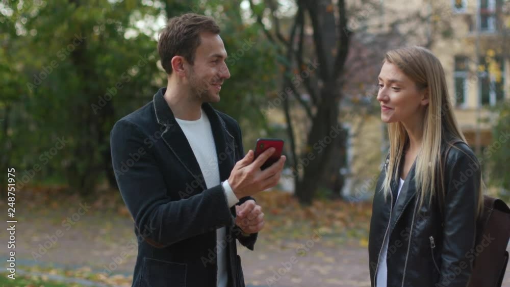 Young beautiful happy couple stand talk use phone hugs lifestyle love male man outdoors woman casual caucasian cell day fashion fun laughing portrait smiling travel vacation close up slow motion Young beautiful happy couple stand talk use phone hugs lifestyle love male man outdoors woman casual caucasian cell day fashion fun laughing portrait smiling travel vacation close up slow motion