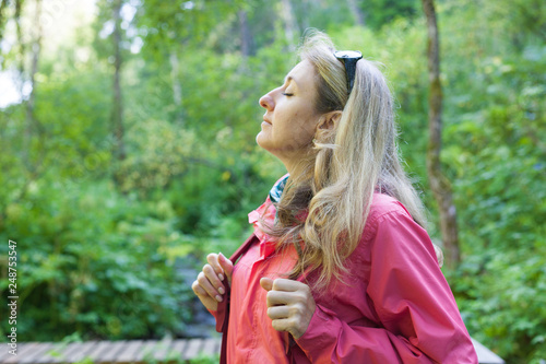 Woman tourist in pink kuruntke with backpack relaxes in the forest